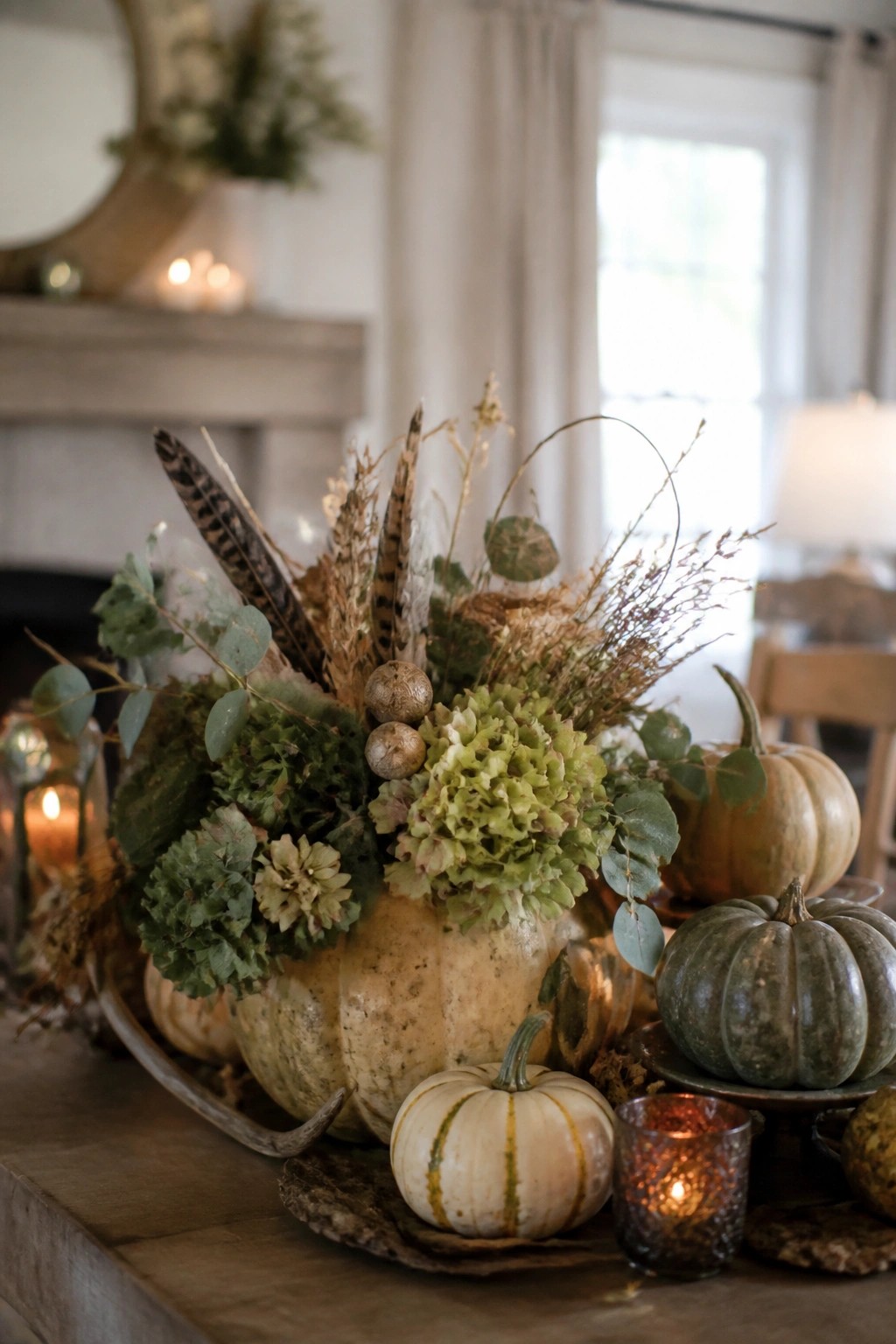 A wooden table displays a large pale pumpkin surrounded by smaller white and green pumpkins on a tray, with lit candles and dried greenery.