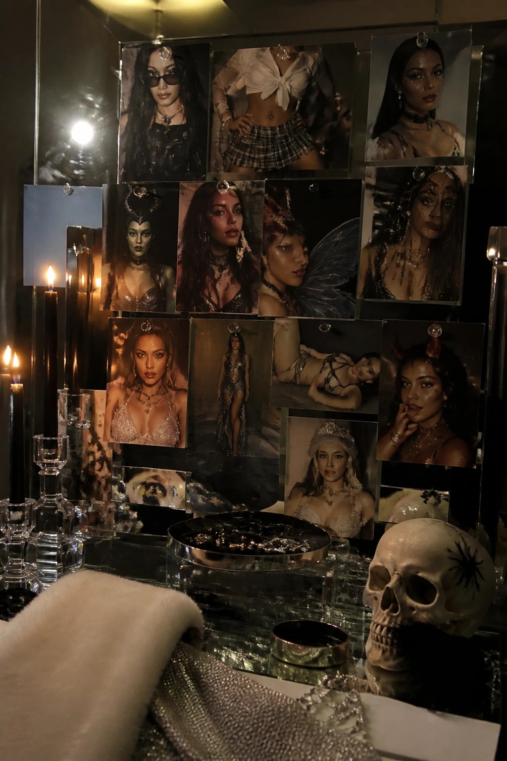 Mirror wall with costumed woman photos, lit candles, jewelry, and skull